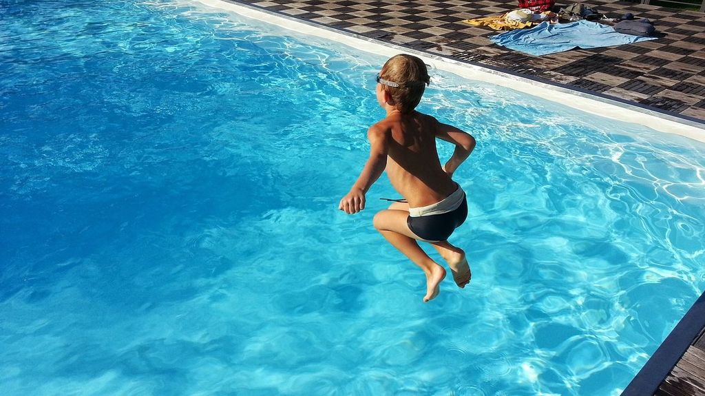 Niño saltando en una piscina