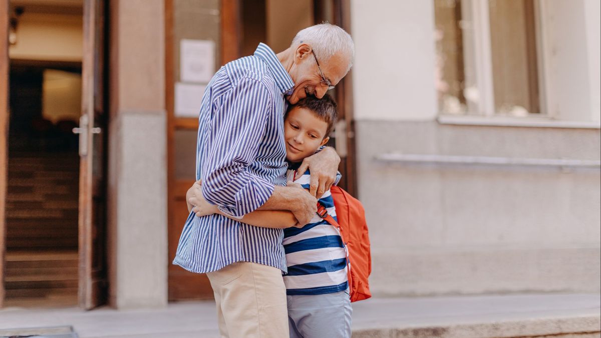 Un abuelo abraza a su nieto a la puerte del colegio