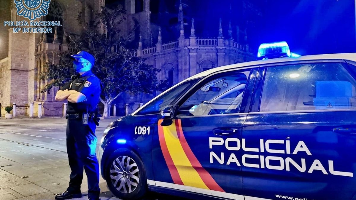 Archivo - Un agente de la Policía Nacional junto a un coche patrulla en una imagen de recurso.