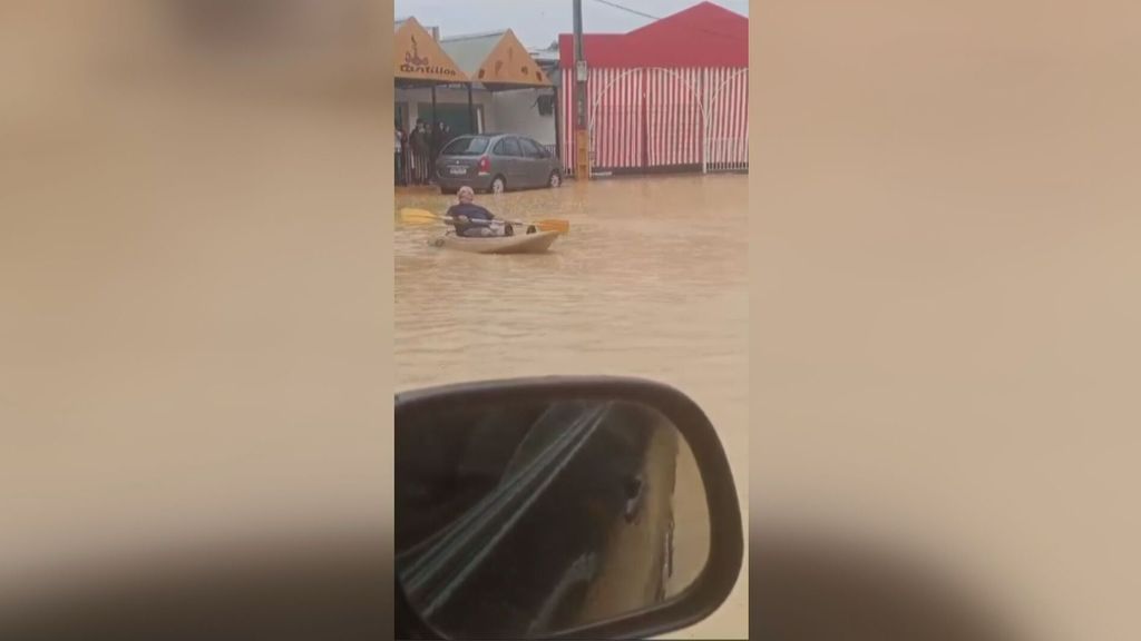 Un hombre rema con su kayak por la feria de Guillena ante las inundaciones dejadas por la DANA