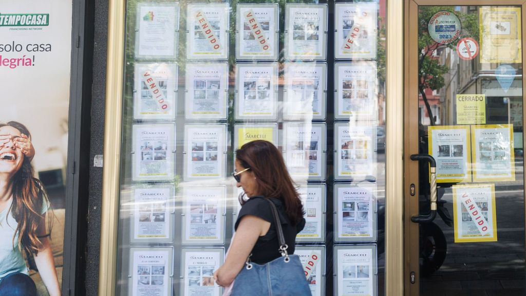 Mujer camina frente a una agencia inmobiliaria