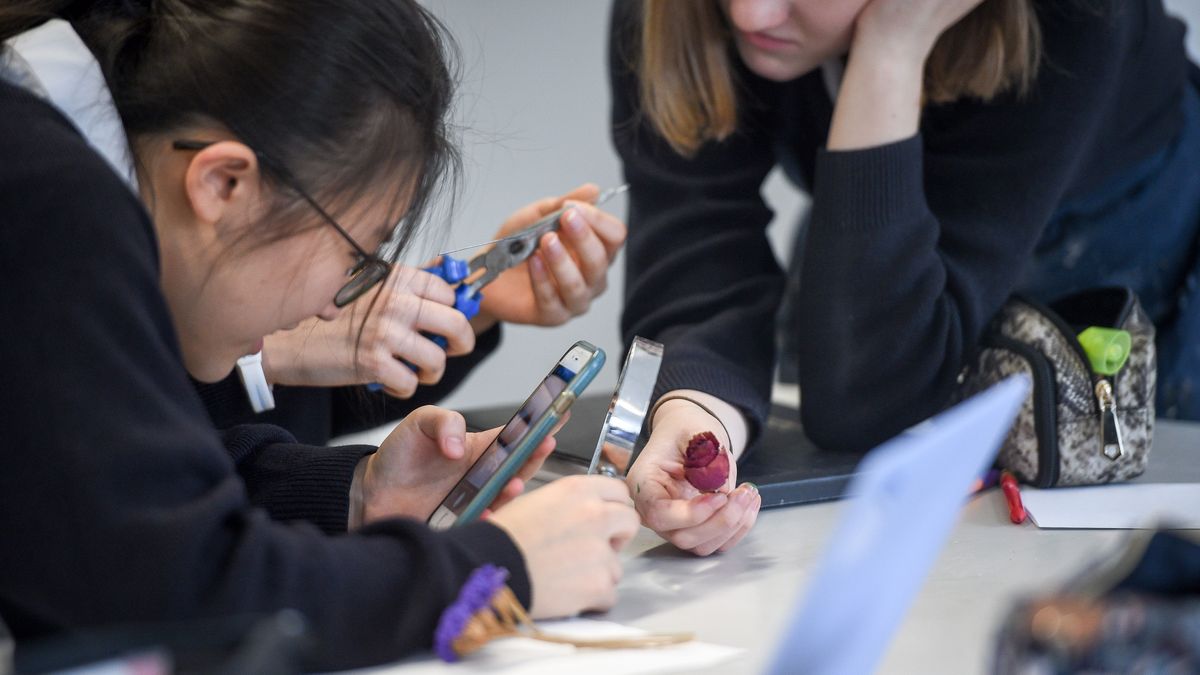 Un grupo de estudiantes juegan con sus dispositivos móviles en su centro educativo