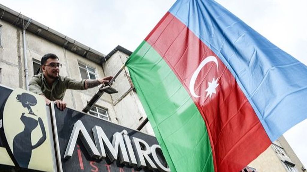 Un residente de la capital de Azerbaiyán cuelga una bandera estatal en Bakú el 20 de septiembre de 2023, en apoyo de la ofensiva del país en la región de Nagorno-Karabaj