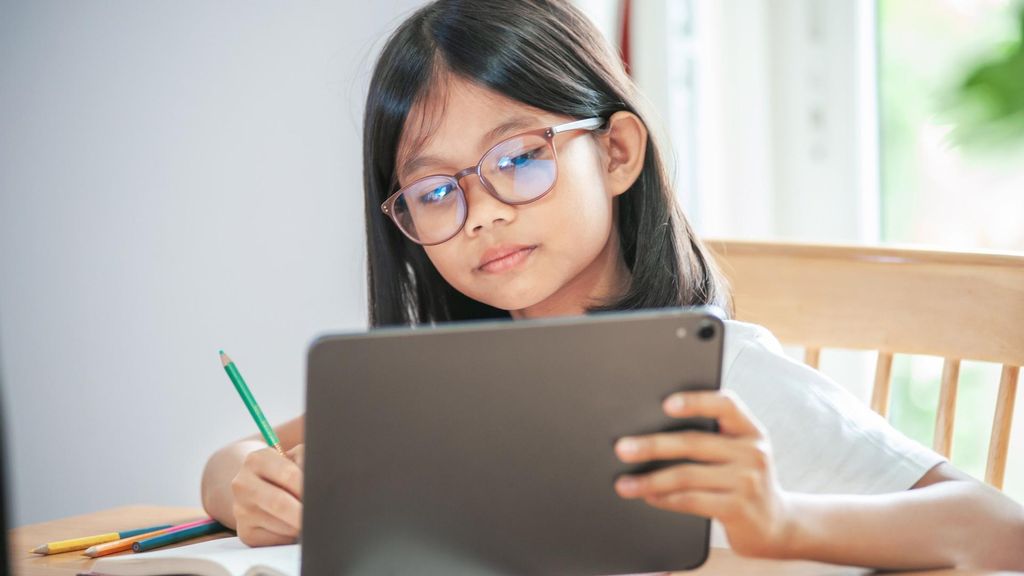 Archivo - Niña con gafas, tarea, tablet, colegio.