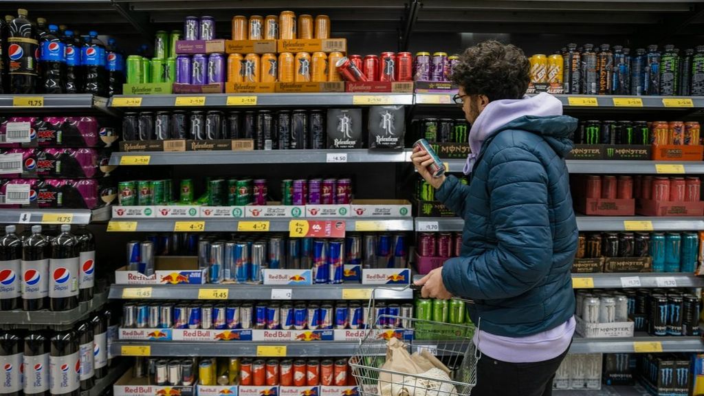 Un joven mira la sección de bebidas energéticas en el supermercado.