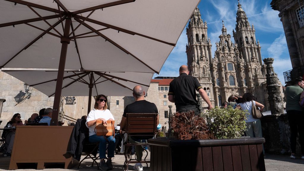 Unos turistas se relajan en una terraza frenta a la Catedral de Santiago de Compostela