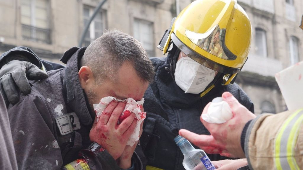 Un bombero herido el rostro es consolado por su compañero