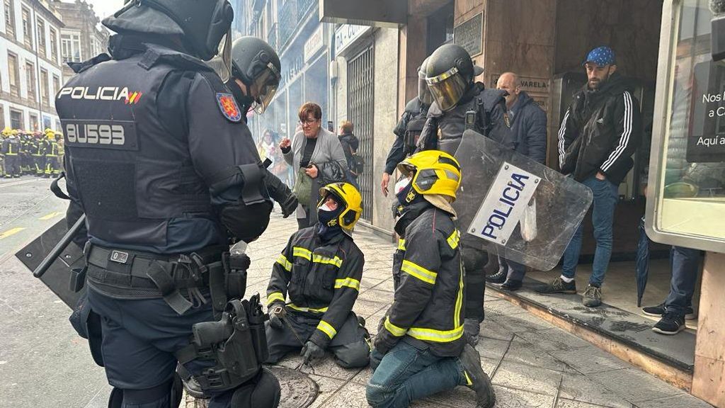 Un policía trata de impedir que los bomberos accedan a la alcantarilla