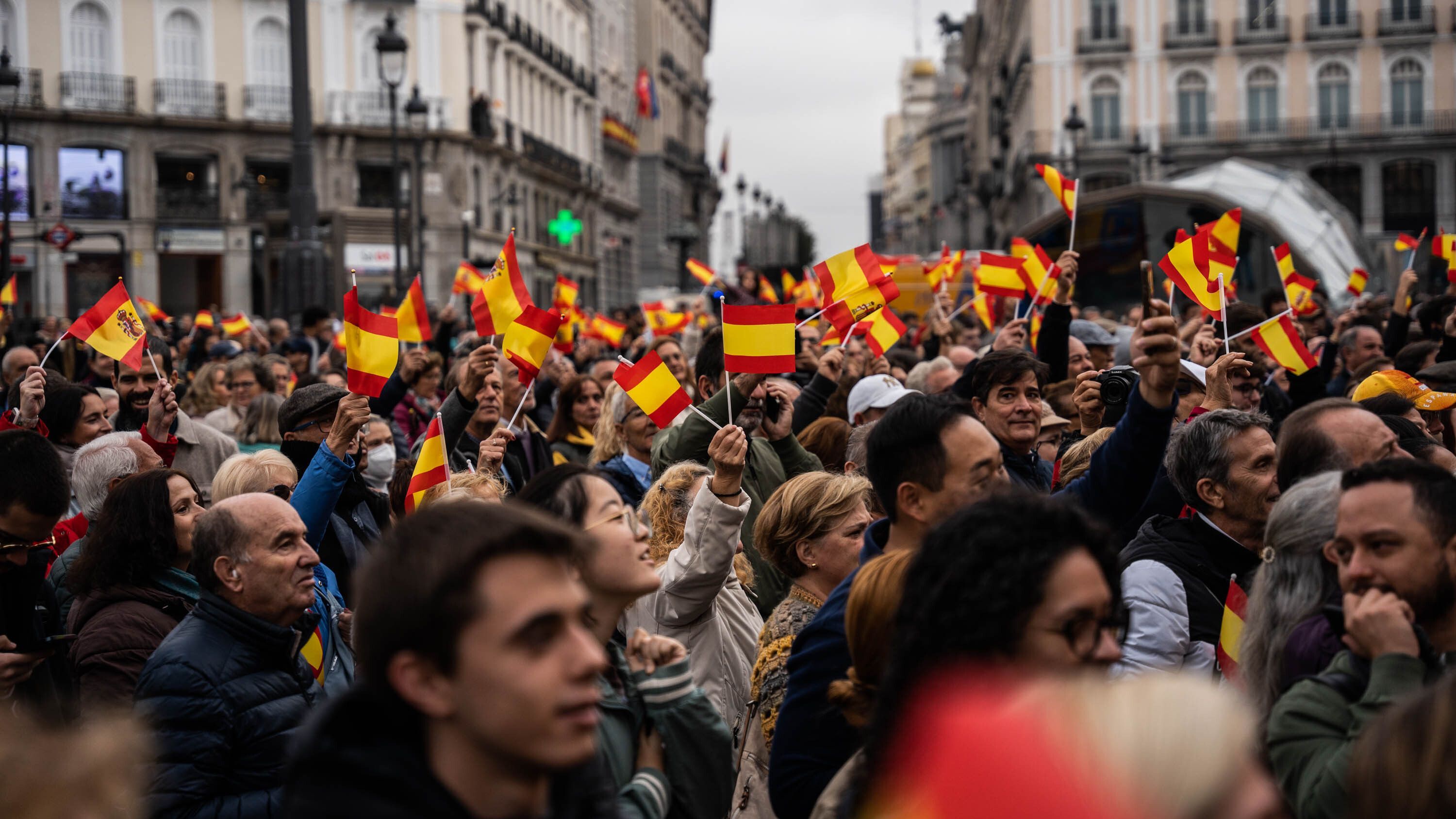 Varias personas con banderas siguen en pantallas, preparadas para la ocasión, el Juramento de la Constitución de la Princesa Leonor, en la Puerta del Sol, a 31 de octubre de 2023, en Madrid (España).