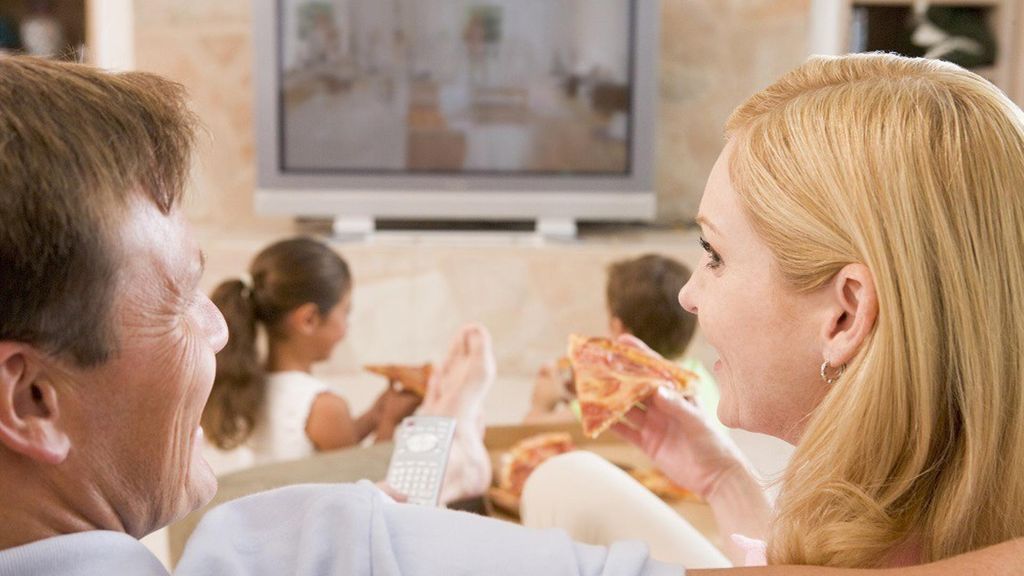 Archivo - Familia viendo la televisión, comer, comiendo