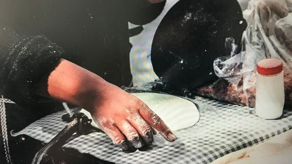 La mano de una mujer manchada de harina durante la elaboración de un talo