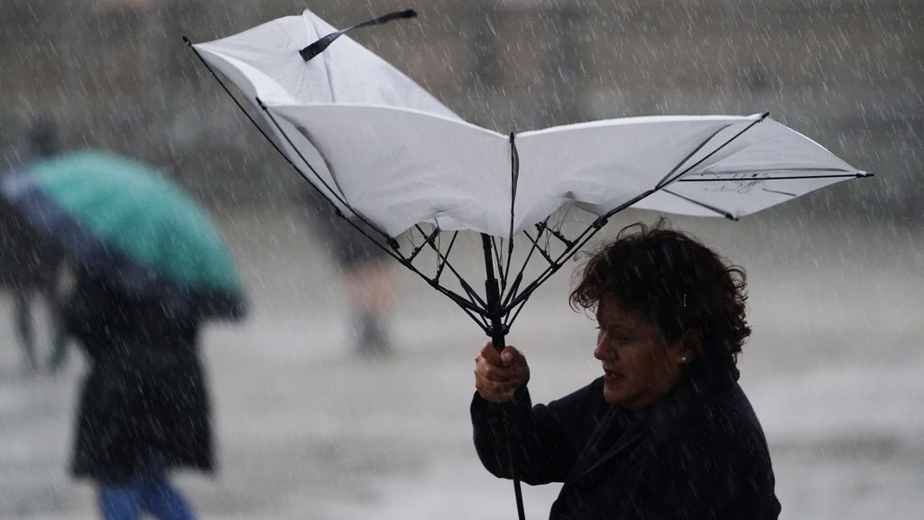 Una mujer sujeta su paraguas roto por el temporal en Santiago de Compostela