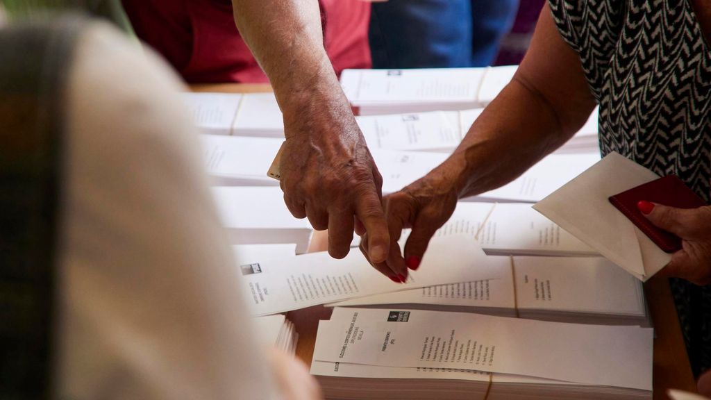 Archivo - Varias personas cogen votos de una mesa electoral, en imagen de archivo