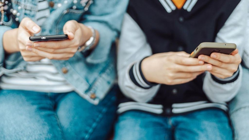 Archivo - Menores de edad miran sus teléfonos móviles.