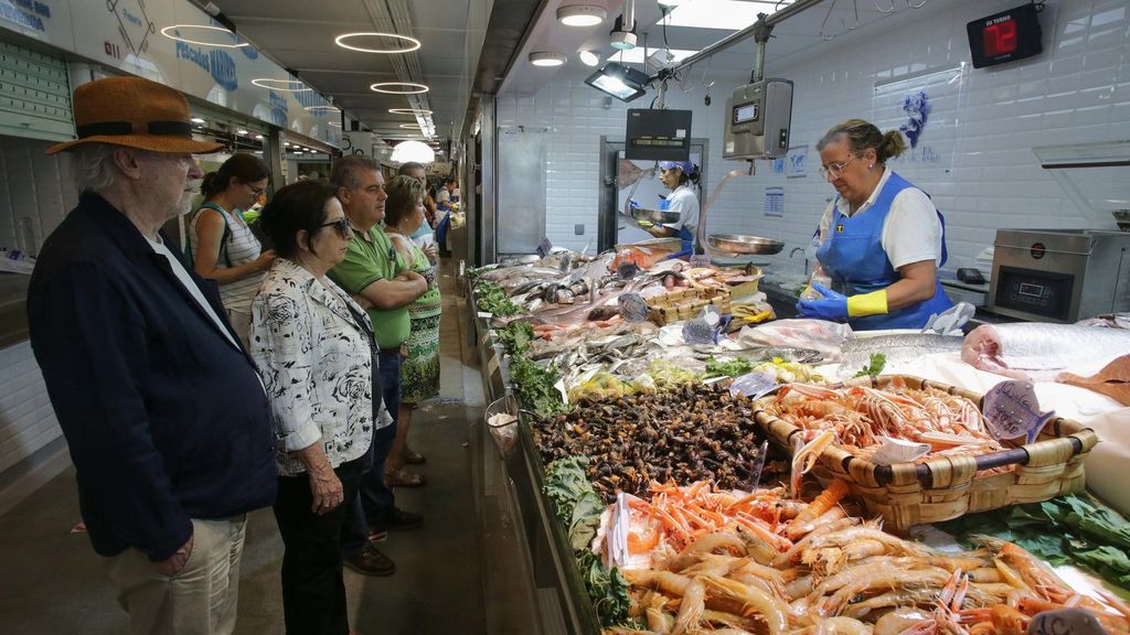 Archivo - Varias personas comprando alimentos en un mercado