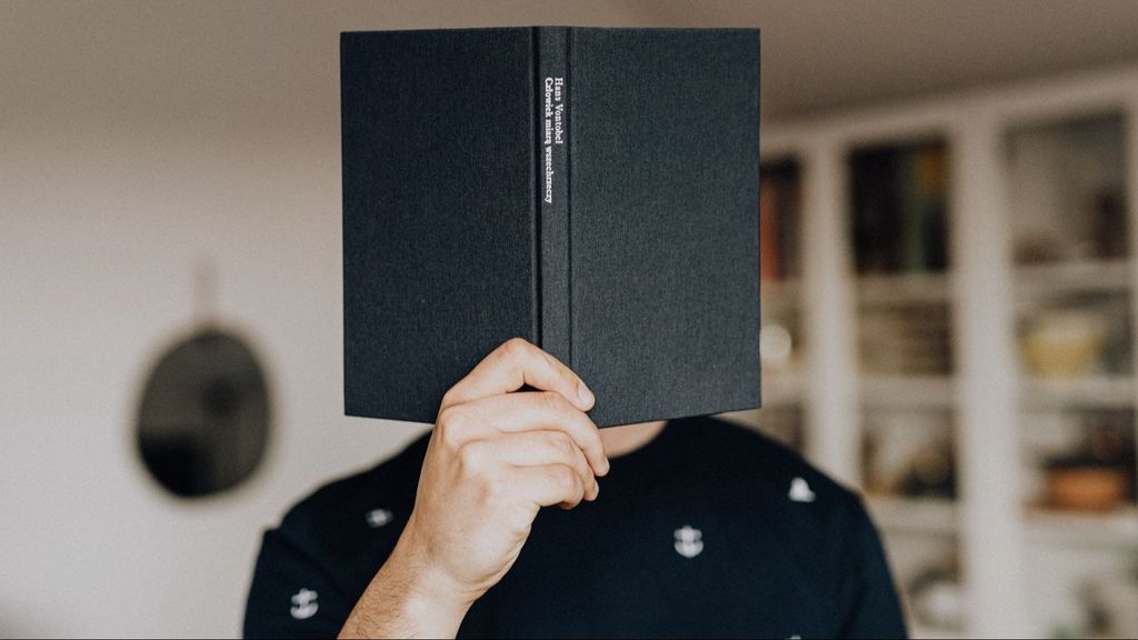 Joven se cubre el rostro con un libro