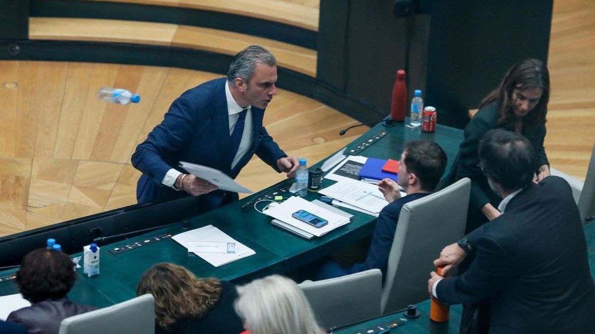 Momento en el que el portavoz de Vox en el Ayuntamiento de Madrid, Javier Ortega Smith, se encara y tira unos papeles y una botella de agua vacía al edil Eduardo Fernández Rubiño, concejal de Más Madrid, en su escaño.