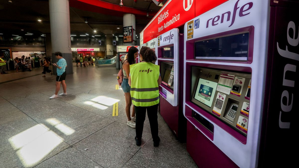 Una trabajadora de Renfe habla con una viajera delante de las máquinas expendedoras de billetes, en la estación de Atocha