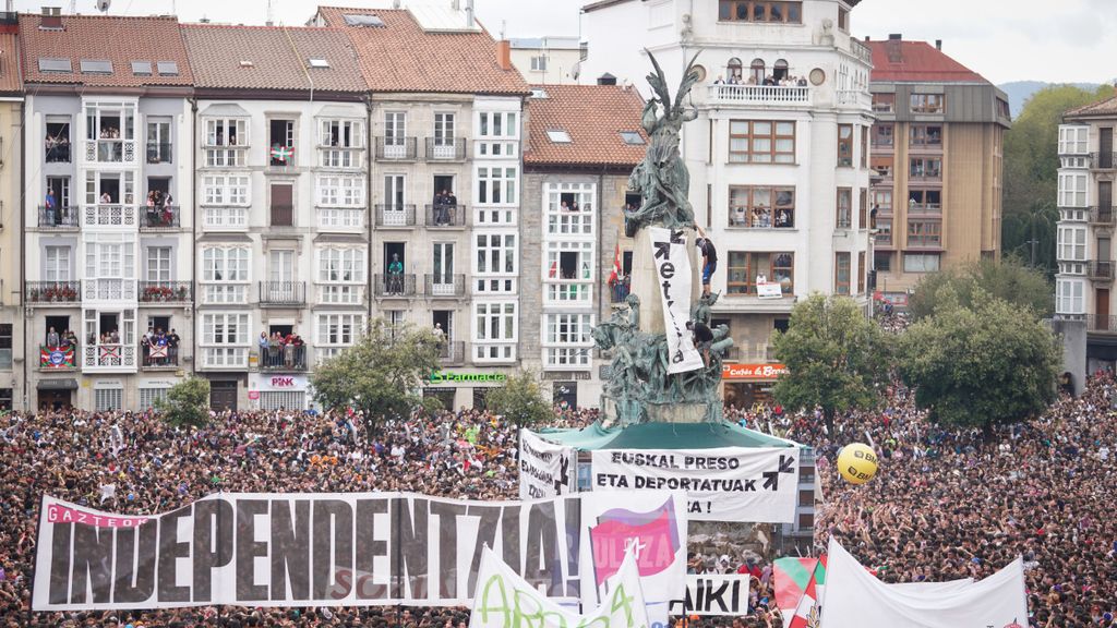 Pancartas y varias personas subidas a la escultura durante el arranque de las fiestas de Vitoria
