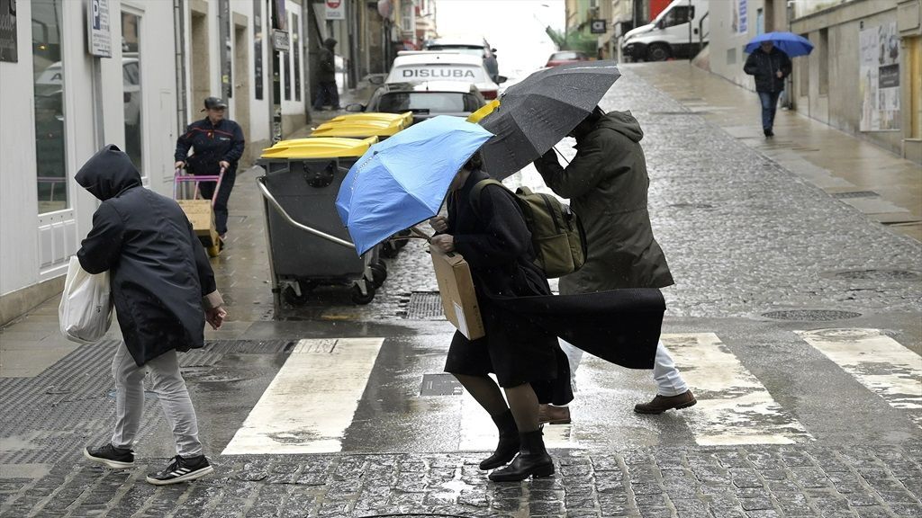 Varias personas se refugian del viento con paraguas, durante la borrasca Karlotta, en A Coruña (Galicia)