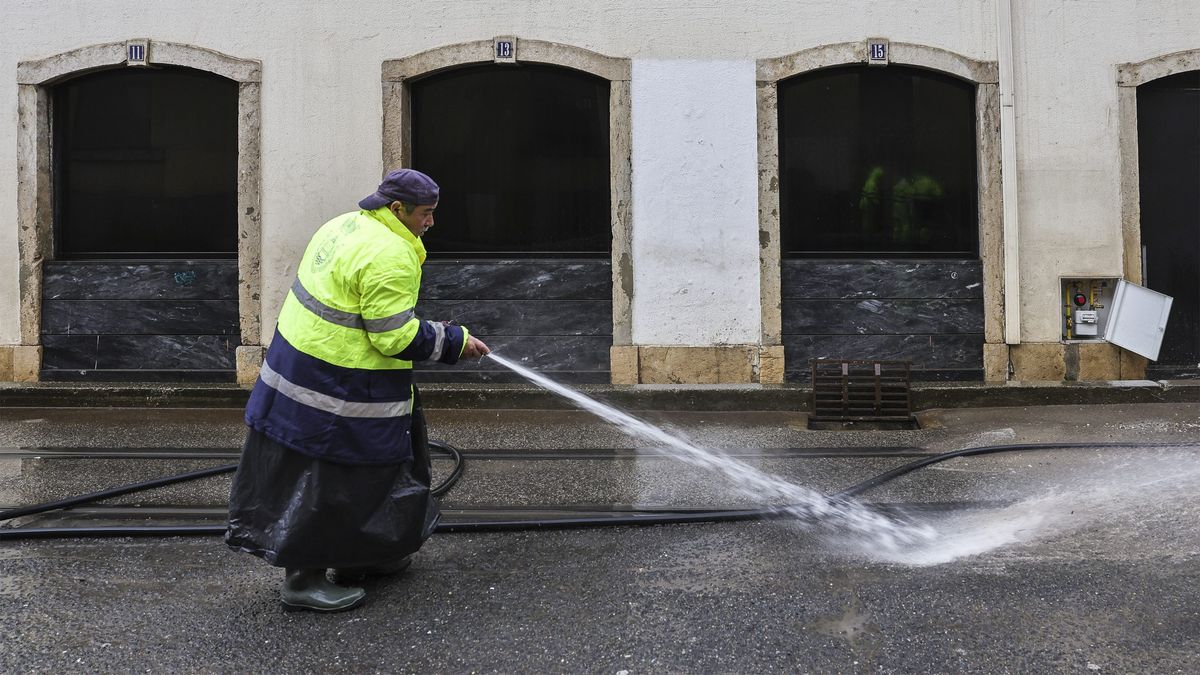 Un trabajador de la limpieza baldea una calle