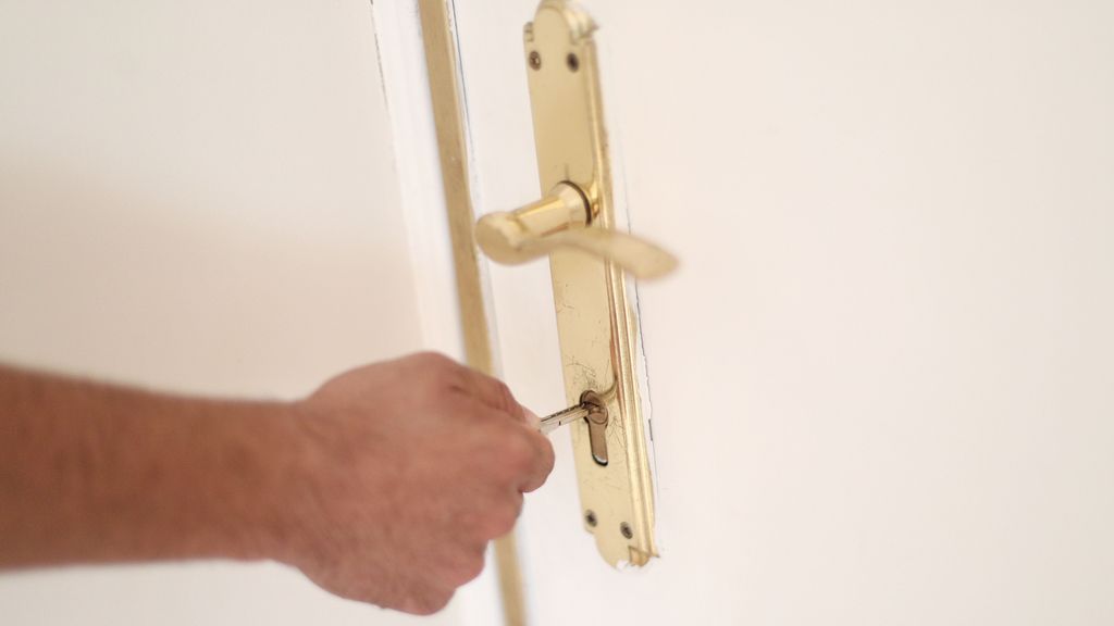 Una persona introduce la llave en la cerradura de una vivienda