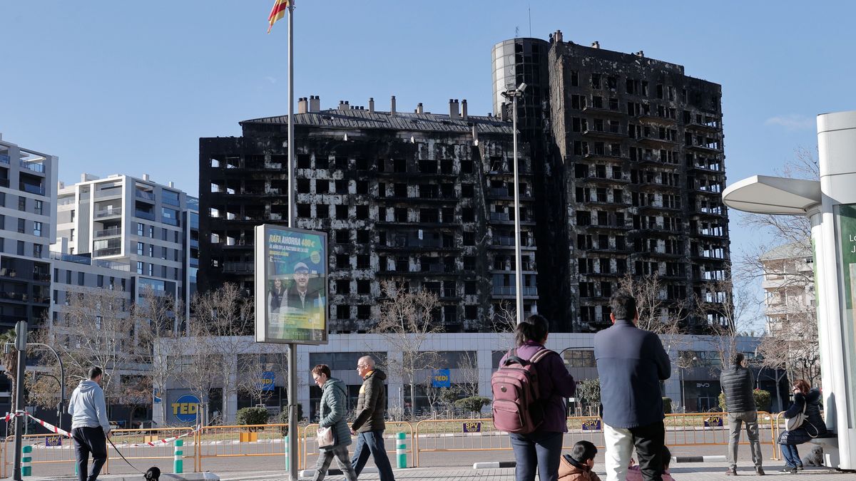 Varias personas observan esta mañana de sábado el edificio incendiado en el barrio de Campanar de València
