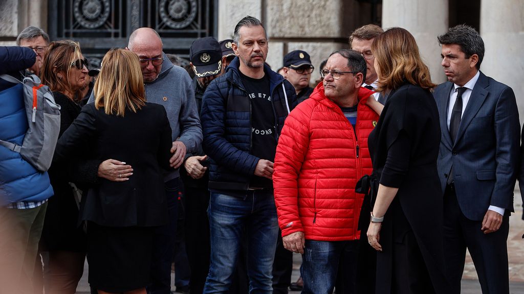 El portero del edificio incendiado, de rojo, junto a las autoridades valencianas