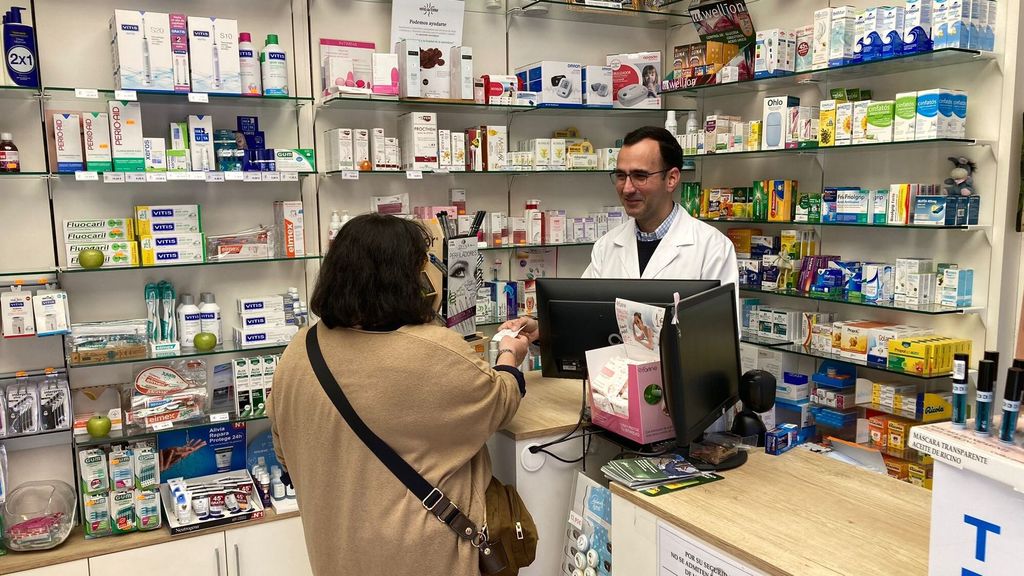 Un farmaceútico de Bilbao atiende a una clienta el primer día en el que los tickets incluirán el teléfono SATEVI