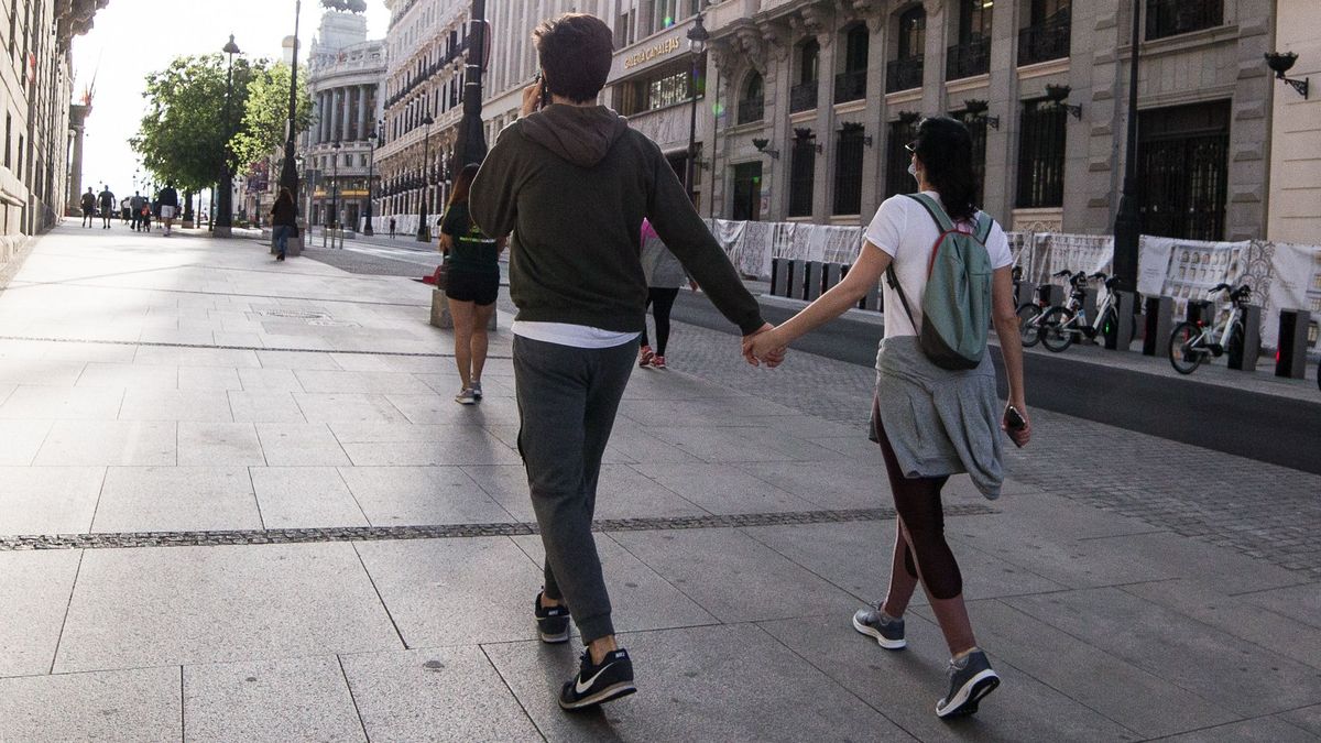 Una pareja pasea de la mano por la calle