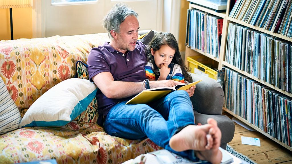 Un padre con una hija viendo un álbum de fotos familiar