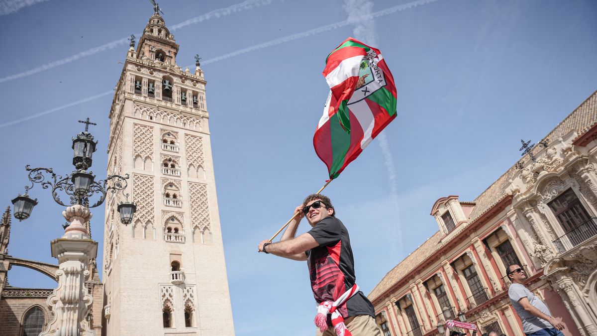 Un aficionado del Athletic Club con una bandera del equipo, con la Giralda de Sevilla al fondo