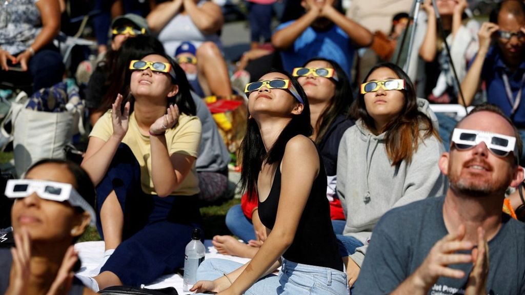Gente con gafas especiales viendo el ecplipse solar