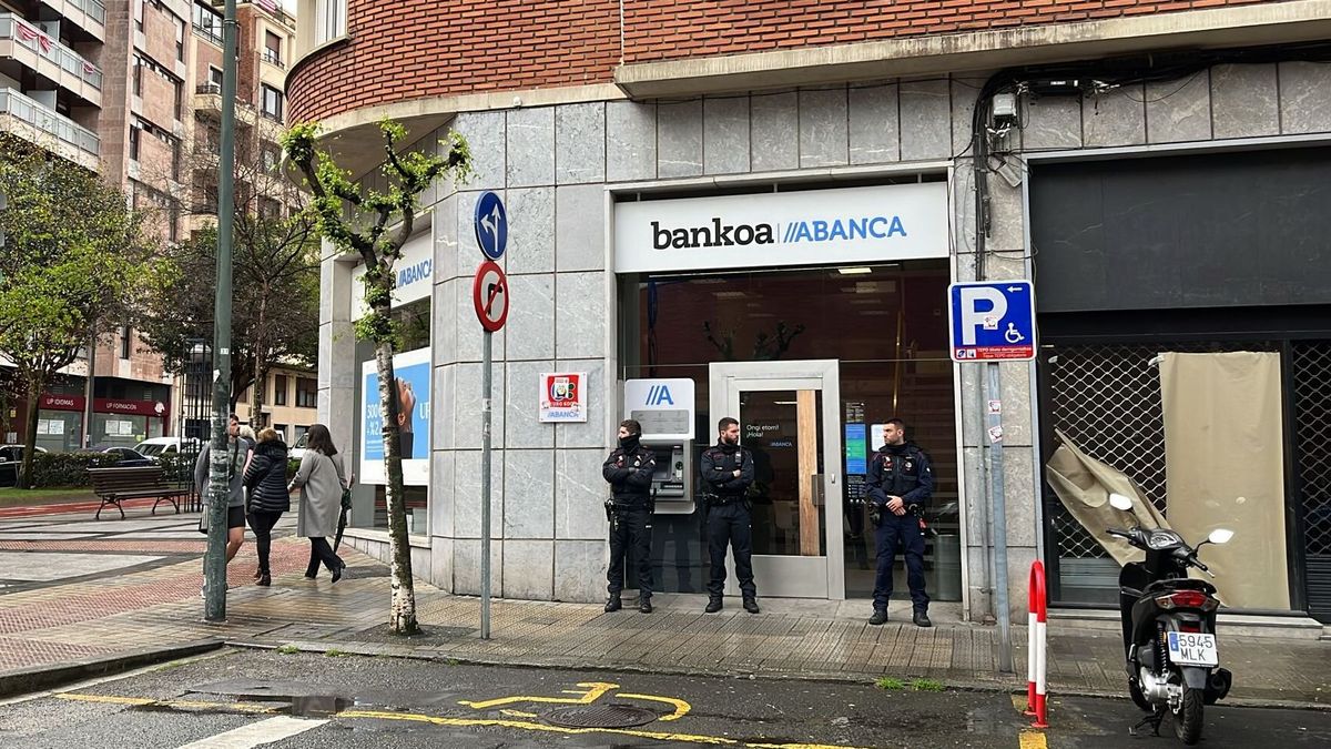 Ertzainas ante la puerta de la sucursal bancaria donde se ha cometido el atrac