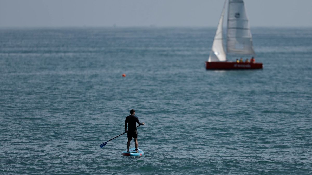 Un hombrese adentra en el mar en su tabla de padel surf
