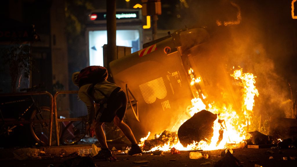Un manifestante frente a un contenedor que arde durante los disturbios en la Plaza de Urquinaona, en Barcelona a 18 de octubre de 2019.