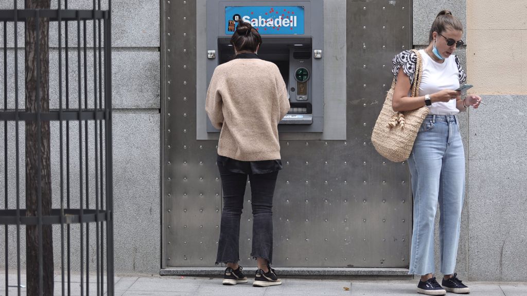 Una clienta del Banco Sabadell saca dinero de un cajero de la entidad en una sucursal de Madrid