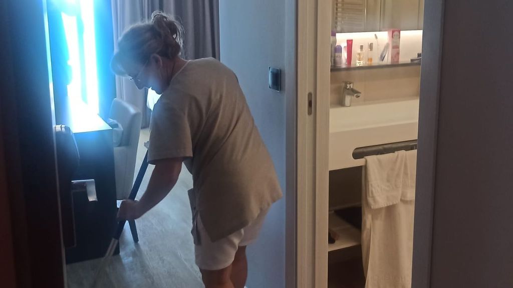 Una camarera de piso arreglando una habitación de hotel