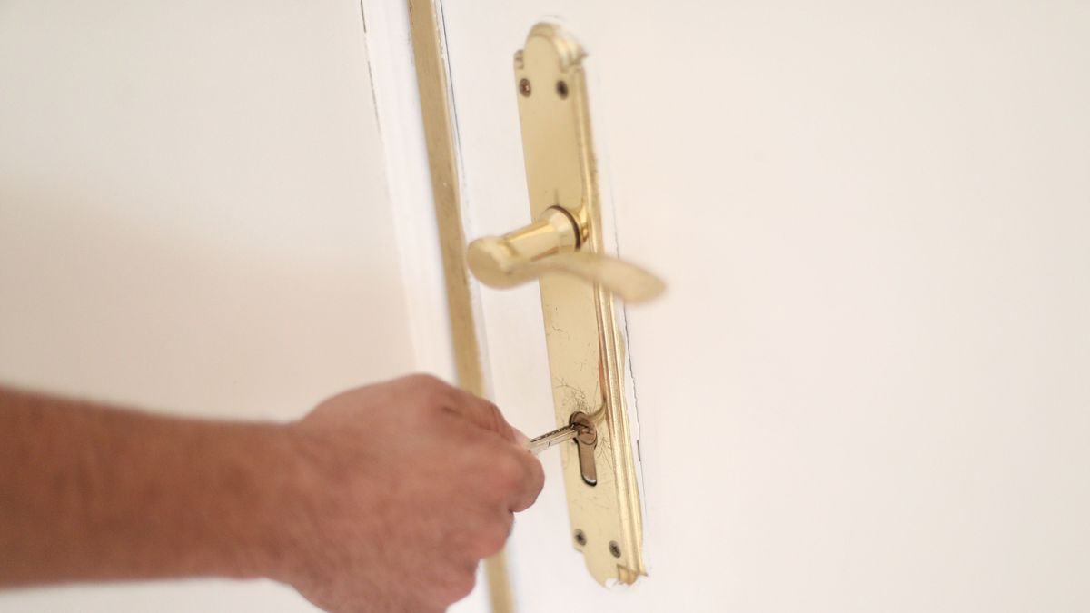 Imagen de archivo de un hombre echando la llave en la cerradura de su casa