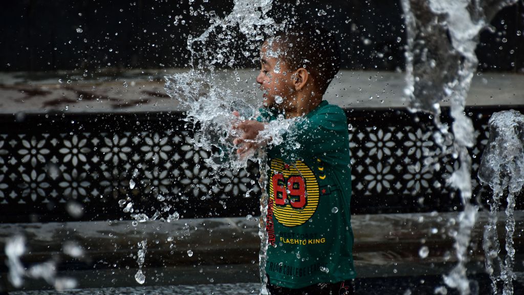 Un niño juega con agua para refrescarse y aliviar el calor en Srinagar, India