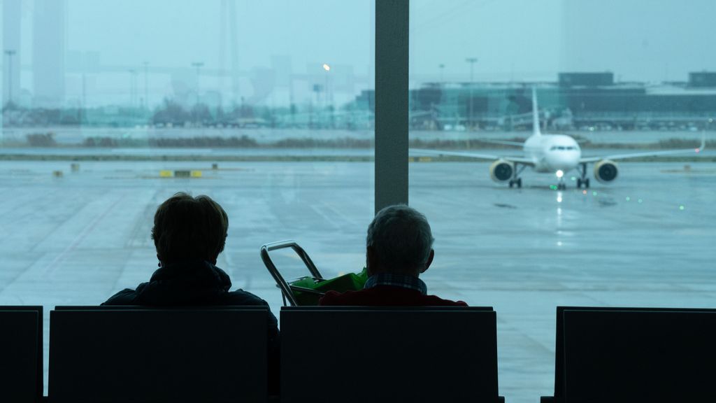 Dos personas esperan en un aeropuerto por la cancelación de su vuelo