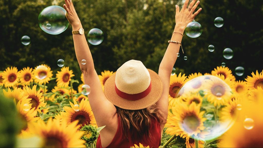 Una mujer, rodeada de girasoles y burbujas