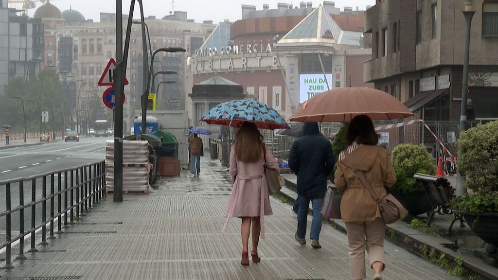 Bilbaínos pasean bajo los paraguas esta mañana en Bilbao