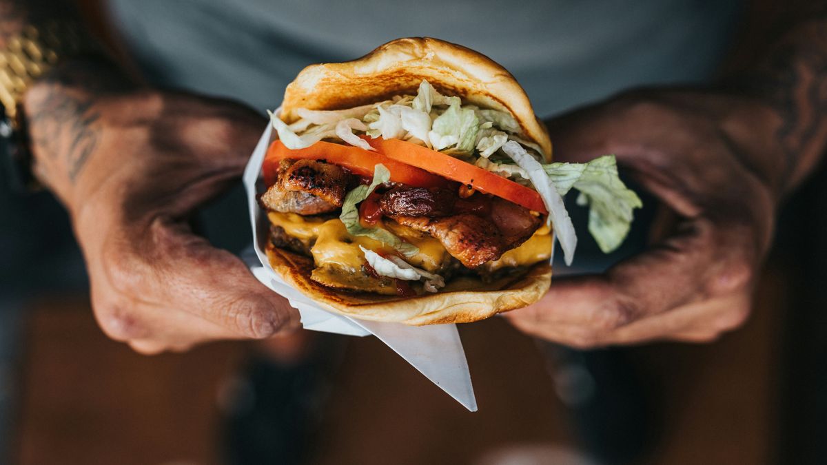 Hombre, con hamburguesa en la mano