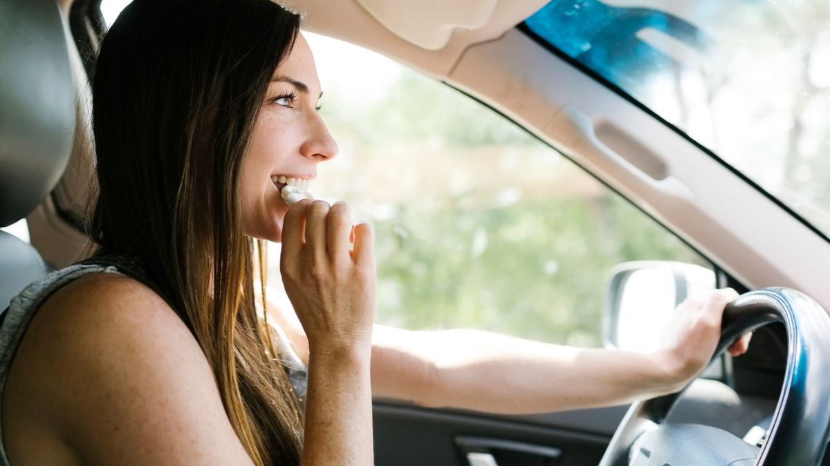 Chica, al volante, comiendo