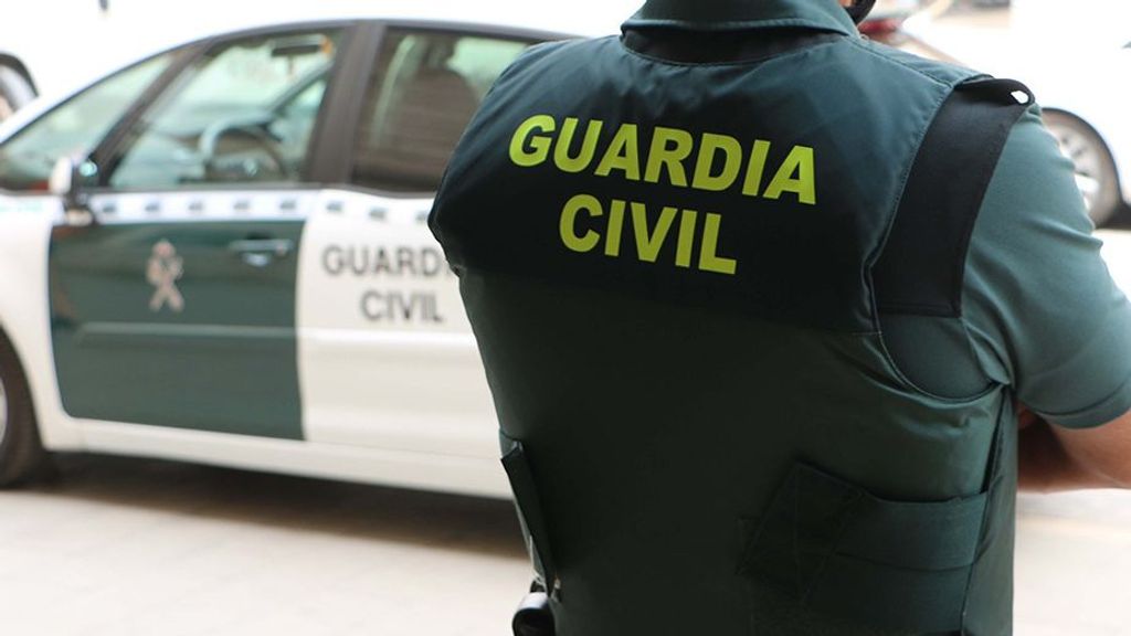 Un agente de la Guardia Civil, de espaldas, junto a un vehículo oficial.