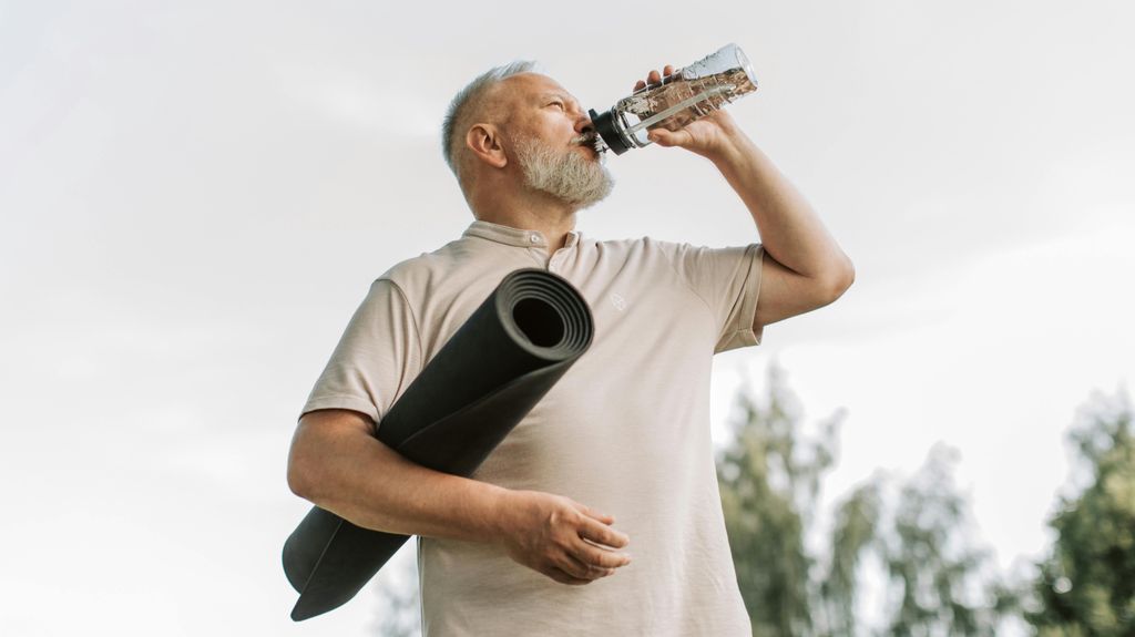 Un hombre bebe agua después de hacer ejercicio