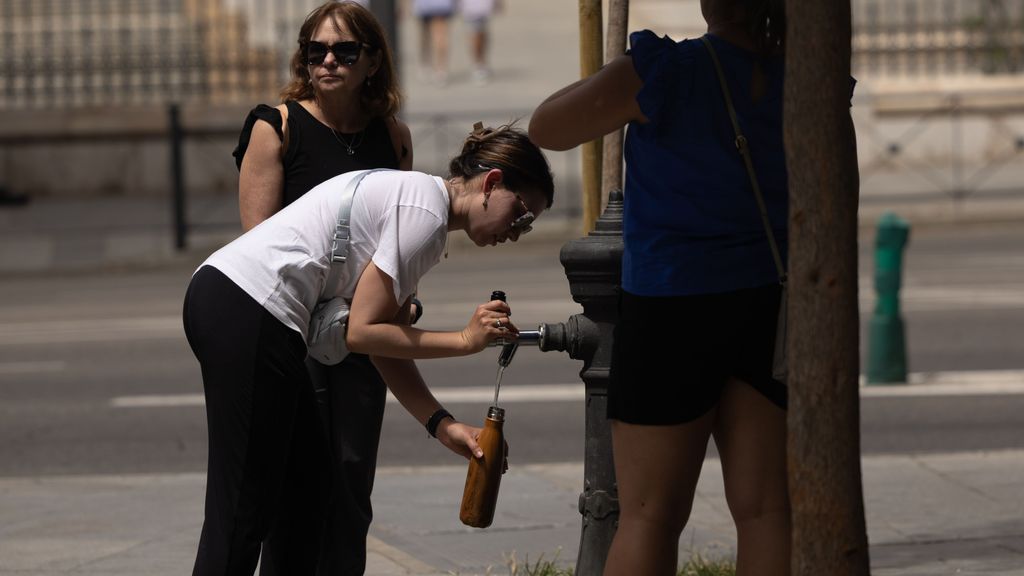 Una mujer rellena una cantimplora en una fuente de Madrid