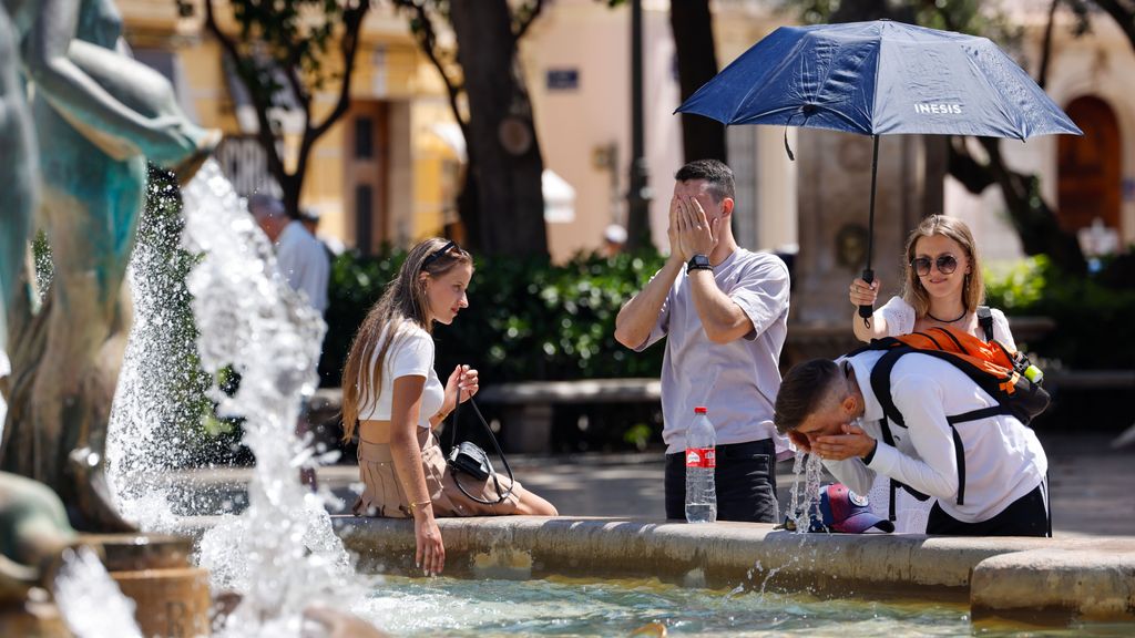 Un grupo de personas se refrescan en una fuente en Valencia cuando la segunda ola de calor llega a su punto álgido