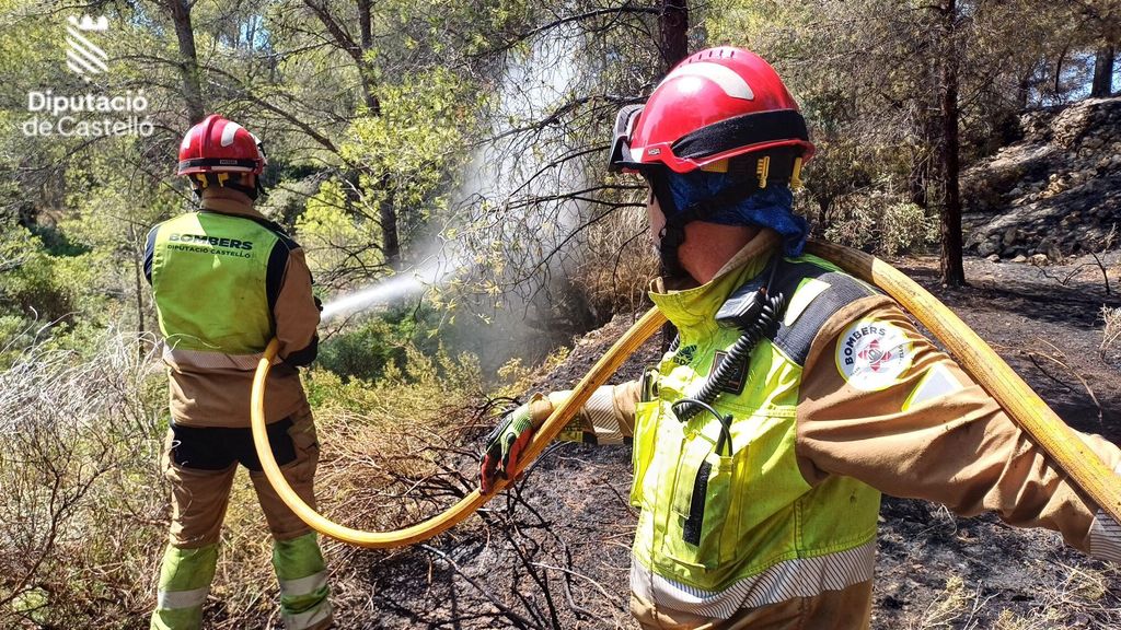 Dos bomberos trabajan para enfriar un incendio controlado en Benicasim, Castellón